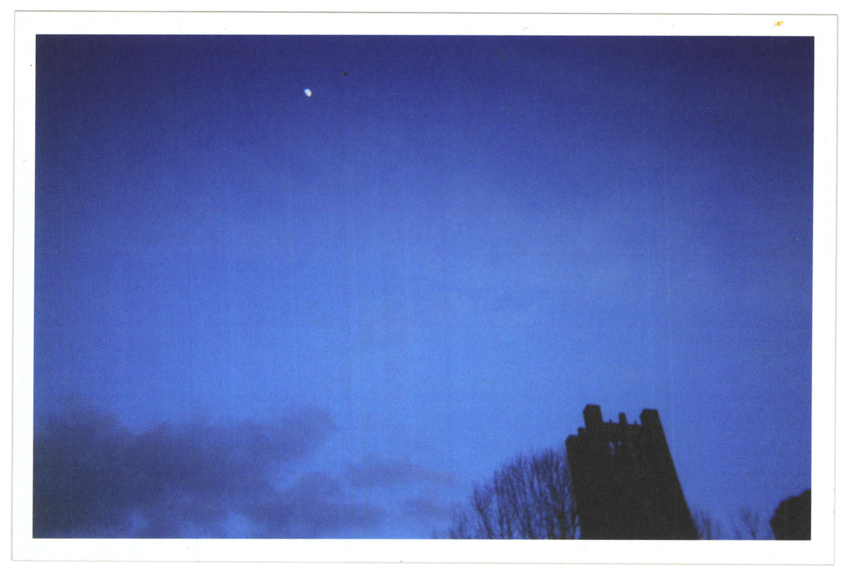 a photograph that's mostly just bright, deep blue: it's of the sky,
      maybe at dusk. in one corner there's a tiny bright smear that must be the
      moon. in the opposite corner, the silhouettes of the tops of a tower and tree.